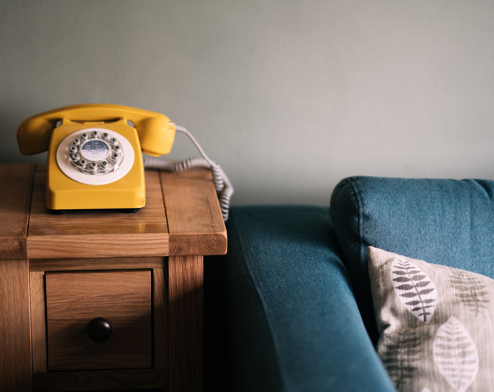 a yellow telephone on top of a wooden table